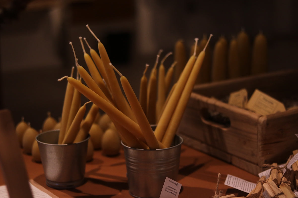 Tall, thin yellow candles in metal containers